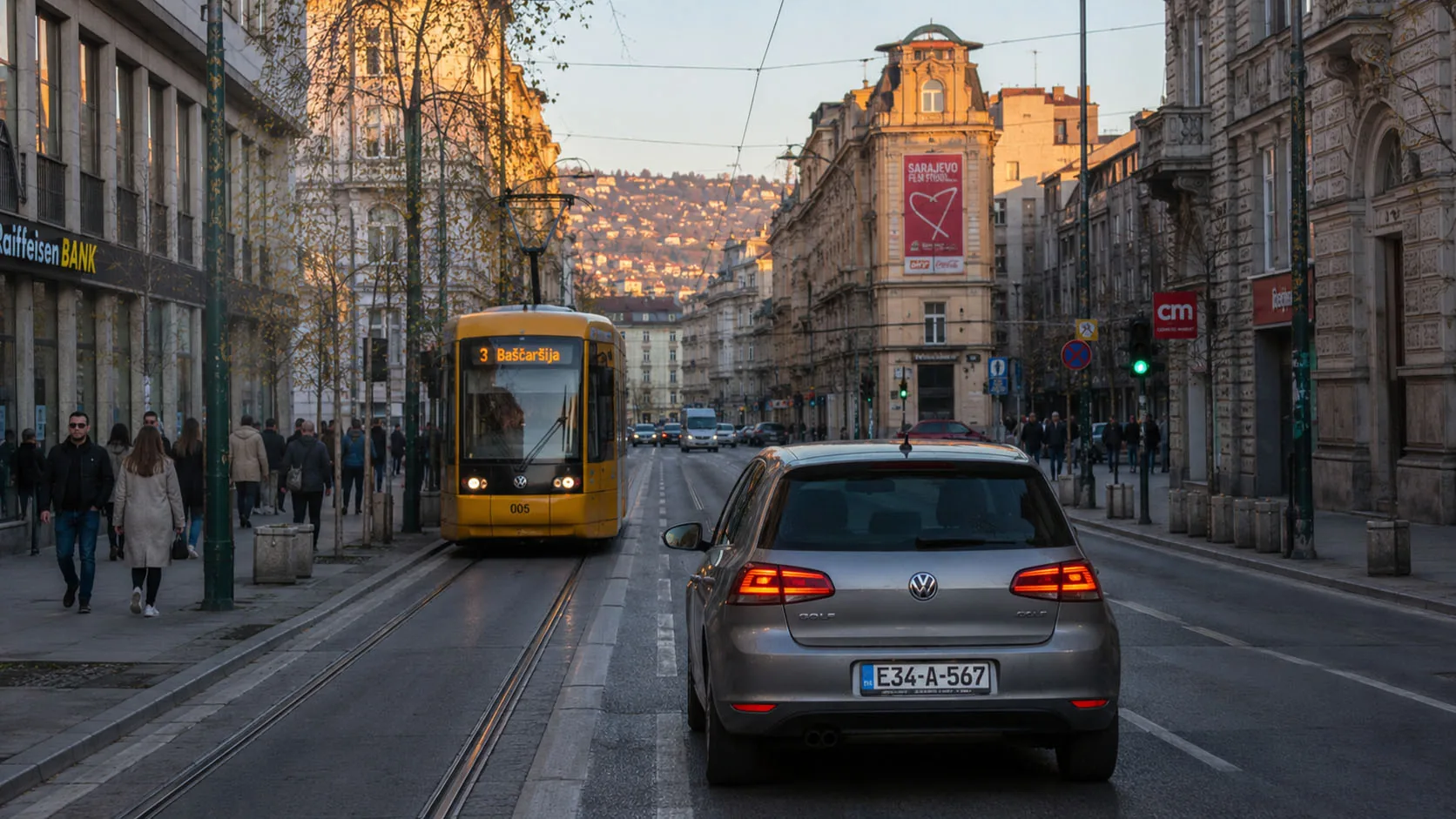 Sivi automobil i žuti tramvaj u centru Sarajeva u kasno popodne