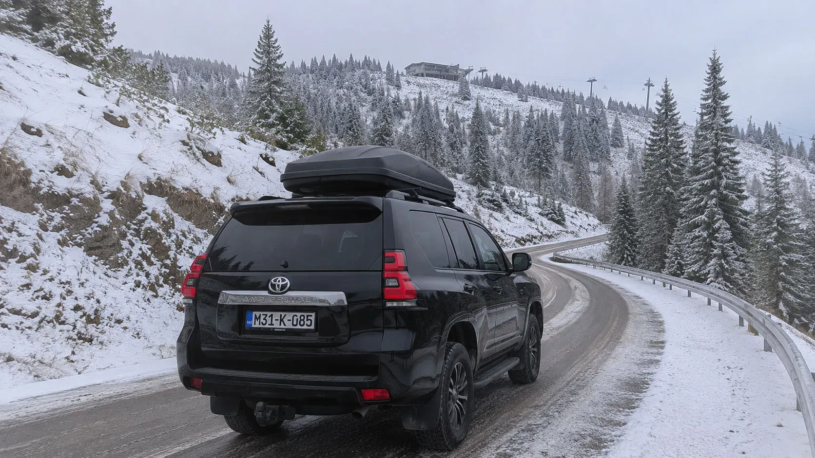 SUV vozilo na zavojitom planinskom putu prema skijalištu tokom zime